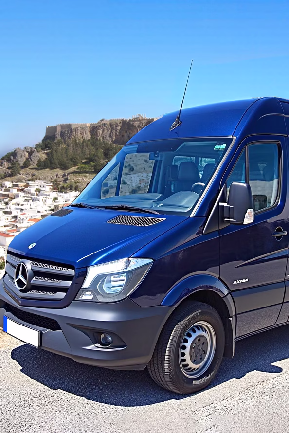 Minivan with a view of Lindos, in the background, representing taxi and shuttle services on demand.